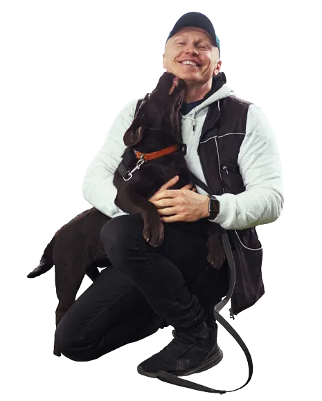 Dog trainer sitting with a black dog, showing a loving bond and positive training approach for transforming dog behavior with love and discipline.